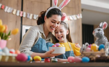 Paskalya yumurtasını evlerinin sıcaklığıyla süslerken bir anne ve kız arasında paylaşılan hoş bir an. Tatil sezonunun neşesi ve yaratıcılığı bu iç açıcı sahnede mükemmel bir şekilde yankılanıyor..