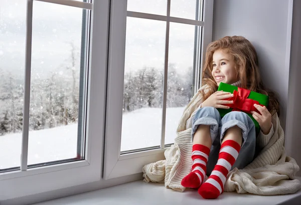 Little girl sitting by the window — Stock Photo, Image