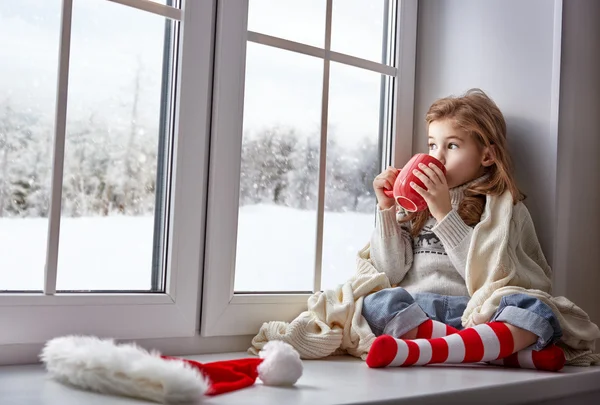 Little girl sitting by the window — Stock Photo, Image