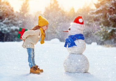 girl playing with a snowman clipart