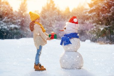 girl playing with a snowman clipart