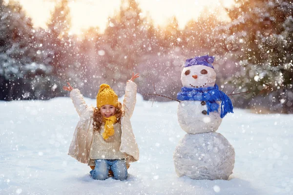 Девушка играет со снеговиком — стоковое фото