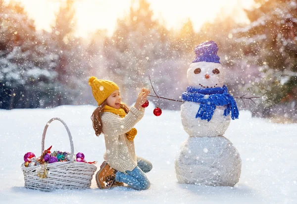 Meisje spelen met een sneeuwpop — Stockfoto