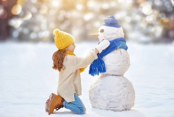 Bir kardan adam ile oynayan kız — Stok fotoğraf