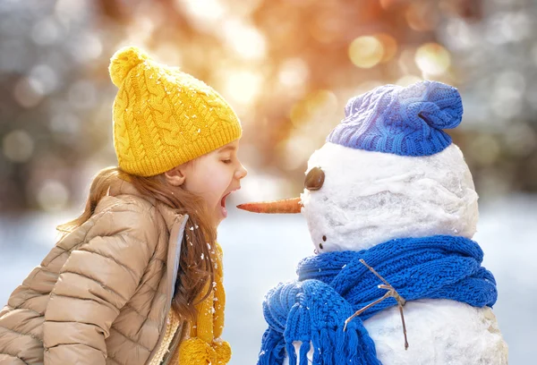 Fille jouer avec un bonhomme de neige — Photo