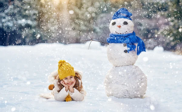Chica jugando con un muñeco de nieve — Foto de Stock
