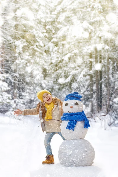 Chica jugando con un muñeco de nieve — Foto de Stock