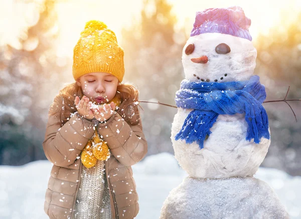 Mädchen spielt mit einem Schneemann — Stockfoto