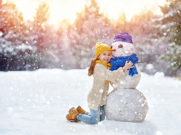 Bir kardan adam ile oynayan kız — Stok fotoğraf
