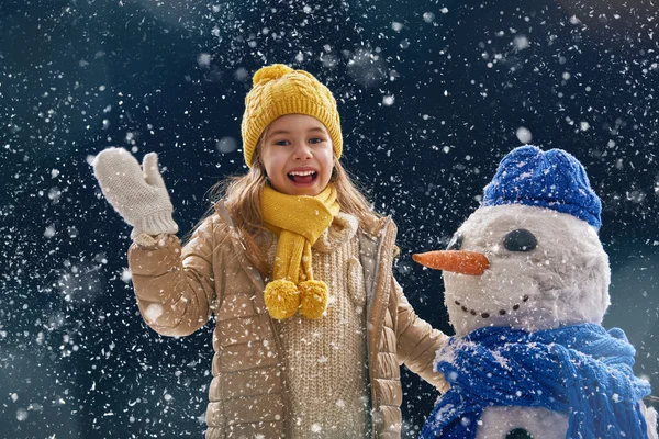 Fille plaçant avec un bonhomme de neige — Photo