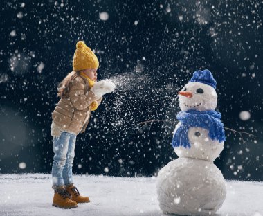 girl plaing with a snowman clipart
