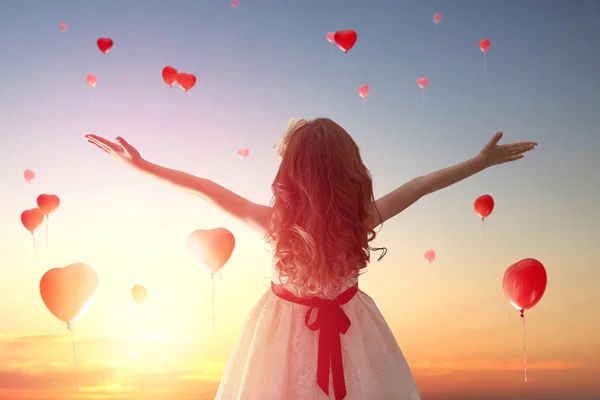 Girl looking at red balloons — Stock Photo, Image