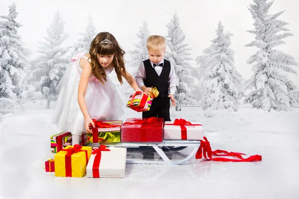 Les enfants portent un tas de cadeaux sur un traîneau . — Photo