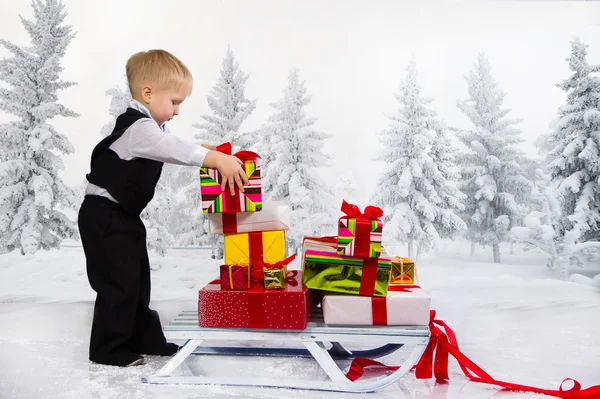 Kinder tragen einen Haufen Geschenke auf einem Schlitten. — Stockfoto