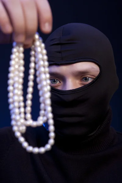 Zloděj. Muž v černé masce s perlový náhrdelník — Stock fotografie