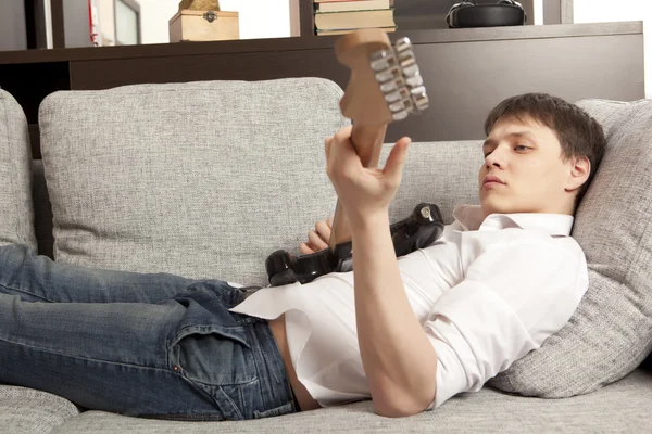 Jeune homme avec guitare électrique sur canapé — Photo