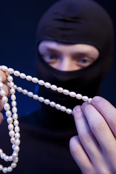 Voleur. Homme en masque noir avec un collier de perles — Photo