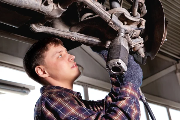 Car mechanic inspecting car wheel and suspension detail of lifte — Stock Photo, Image