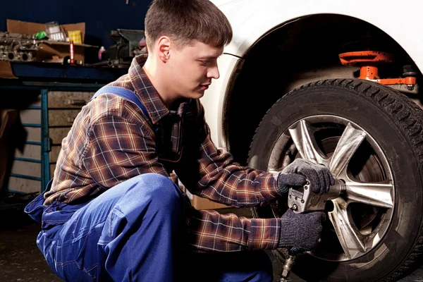 Auto mechanik šroubování nebo vyšroubováním auto kola zdvižené palivové automobil — Stock fotografie