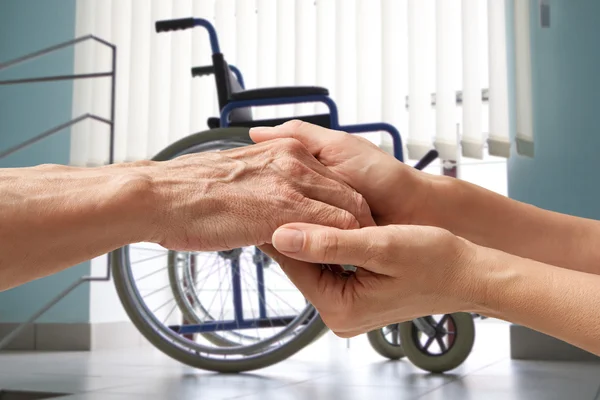 Wwheelchair. Hands of an elderly man holding the hand of a woman — Stock Photo, Image