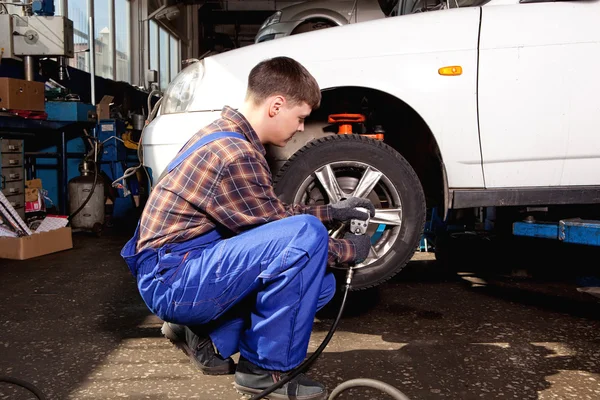 Auto mechanik šroubování nebo vyšroubováním auto kola zdvižené palivové automobil — Stock fotografie