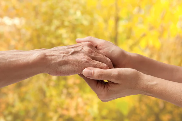 Yaşlı bir kıdemli bir kadının elini tutarak ellerinde — Stok fotoğraf