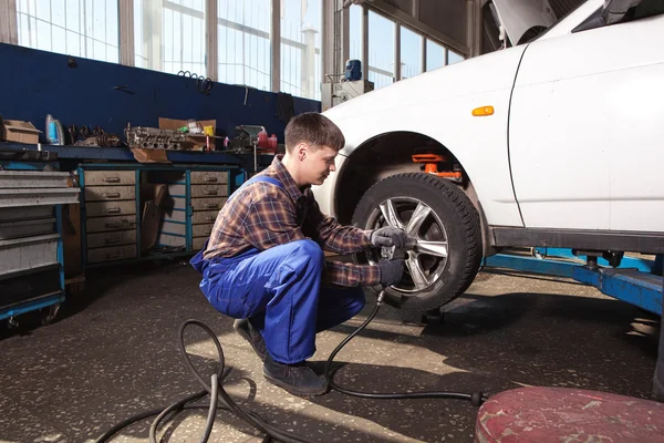 Auto mechanik šroubování nebo vyšroubováním auto kola zdvižené palivové automobil — Stock fotografie