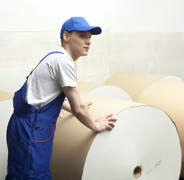 Man pushing huge roll of paper in newspaper factor — Stock Photo, Image