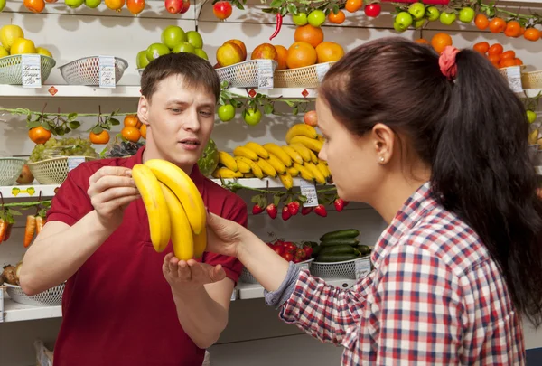 Assistant helping customer at vegetable counter of shop — Stock Photo, Image