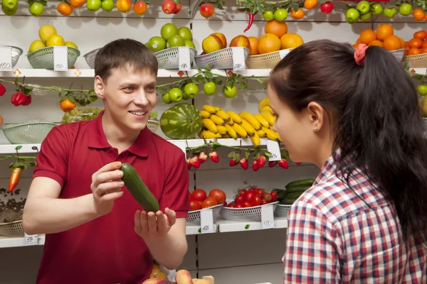 Young woman buys cucumber — Stock Photo, Image