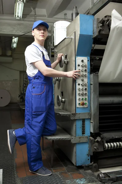 Joven con gorra trabajando en la máquina de impresión offset — Foto de Stock