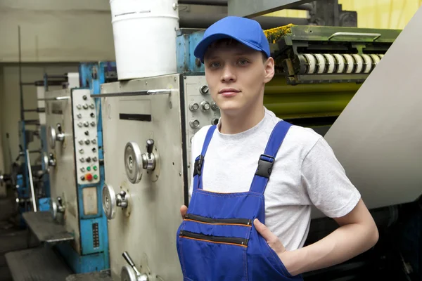 Jovem em cap trabalhando na máquina de impressão offset — Fotografia de Stock