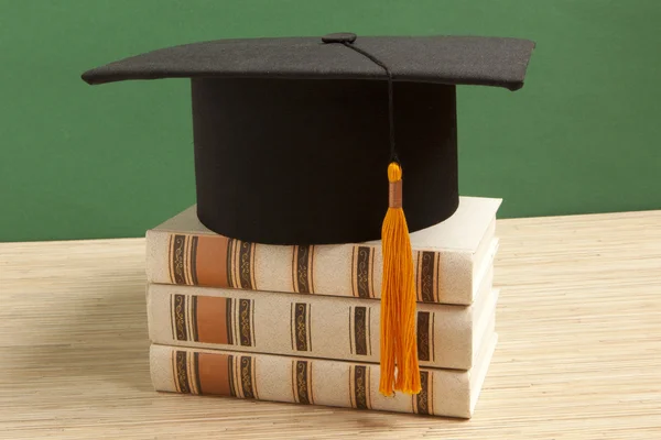 Avläggande av examen hatt med gammal bok — Stockfoto