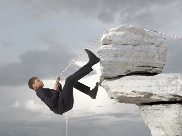 Joven empresario escalando una roca — Foto de Stock