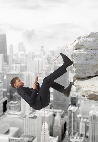 Giovane uomo d'affari scalare una roccia — Foto Stock
