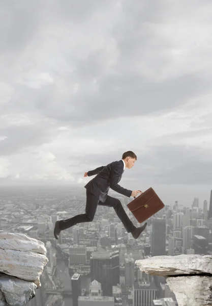 Businessman jumping over rocks — Stock Photo, Image