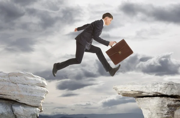 Businessman jumping over rocks Royalty Free Stock Photos