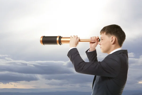 Empresário olha através de um telescópio — Fotografia de Stock