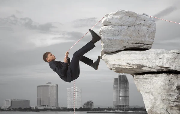 Young businessman scaling a rock — Stock Photo, Image