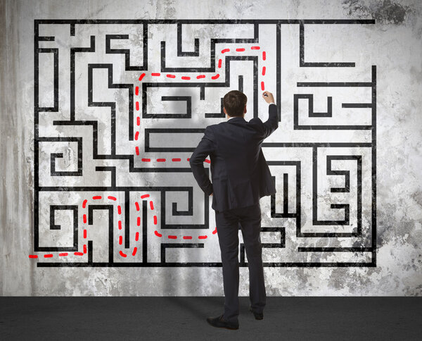 Businessman drawing labyrinth on wall