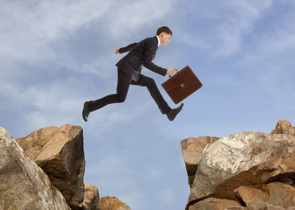 Empresario saltando sobre rocas —  Fotos de Stock