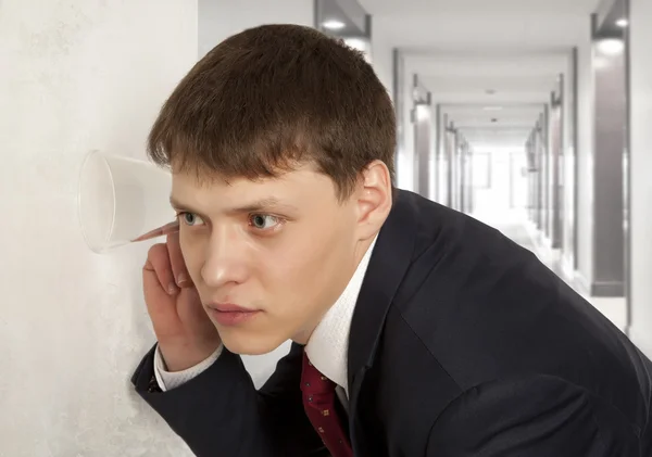 Businessman spying by listening through wall — Stock Photo, Image