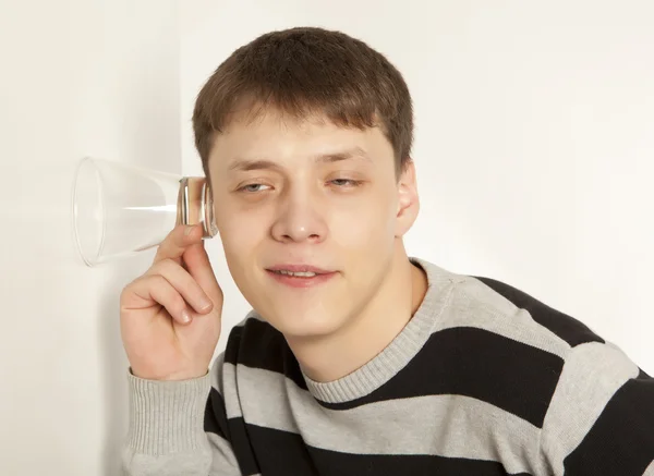 Man spionage door te luisteren via de muur met glas — Stockfoto