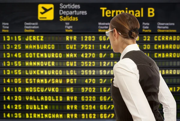 Woman looking to departure board — Stock Photo, Image