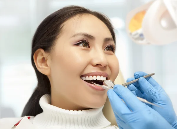 Mujer joven manteniendo la boca abierta mientras el dentista lo examina —  Fotos de Stock