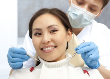 Smiling patient looking at camera while dentist examining it 