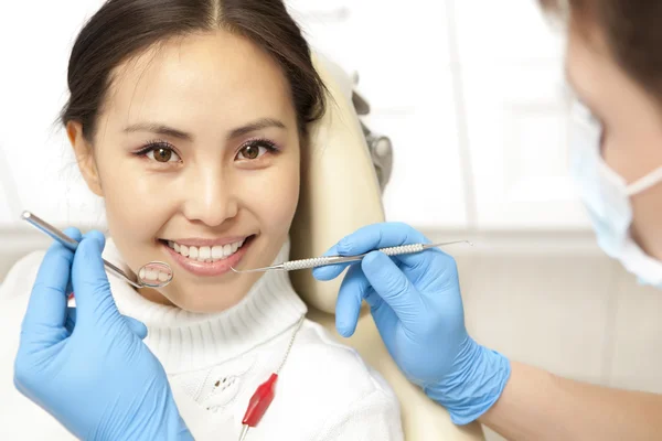 Smiling patient looking at camera while dentist examining it — Zdjęcie stockowe