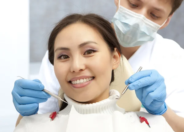 Lächelnder Patient, der in die Kamera schaut, während der Zahnarzt sie untersucht — Stockfoto