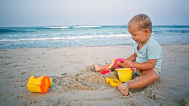 Batole chlapec hraje písek hračky na pláži — Stock video