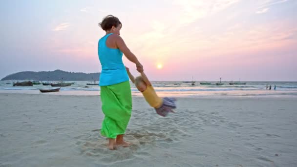 Mãe balançando filho criança por mãos na praia — Vídeo de Stock